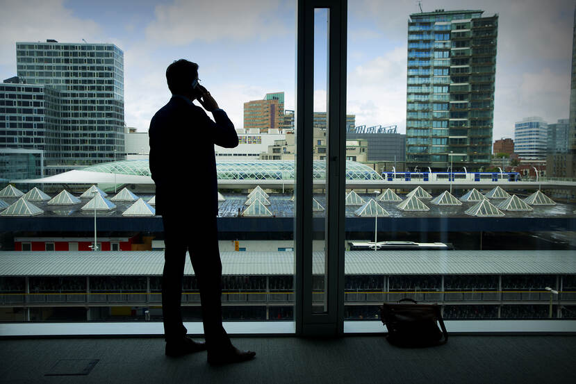 Man telefoneert en kijkt uit het raam